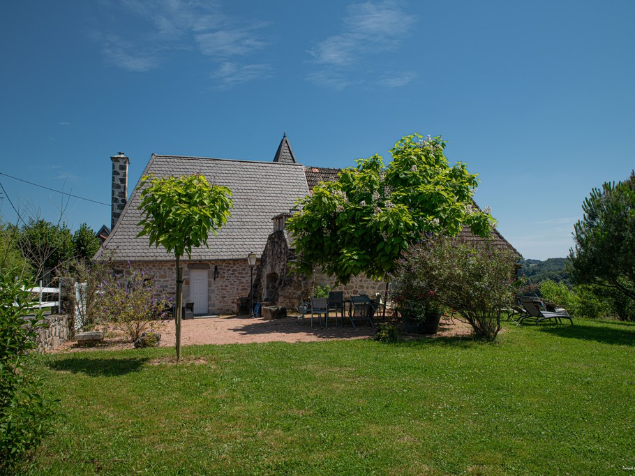 Terrasse du gîte avec barbecue, transats et salon de jardin face à la nature