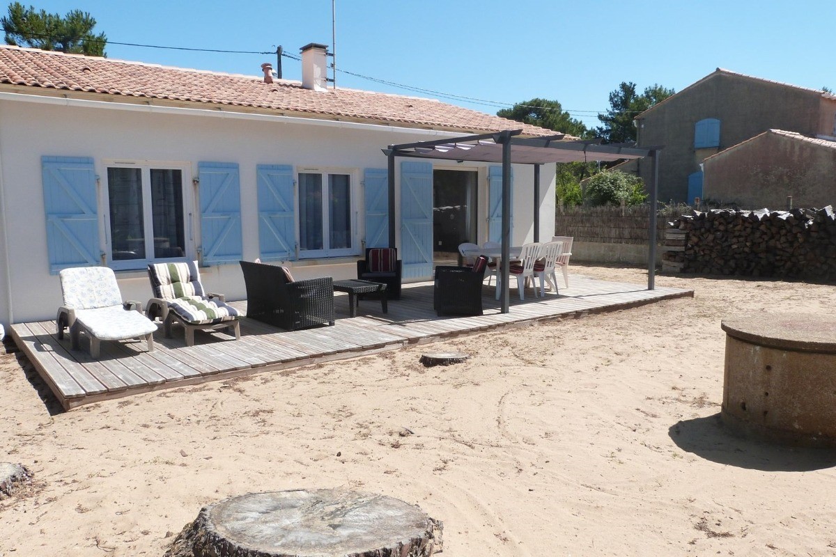 Jardin sablonneux avec salon de jardin et pergola