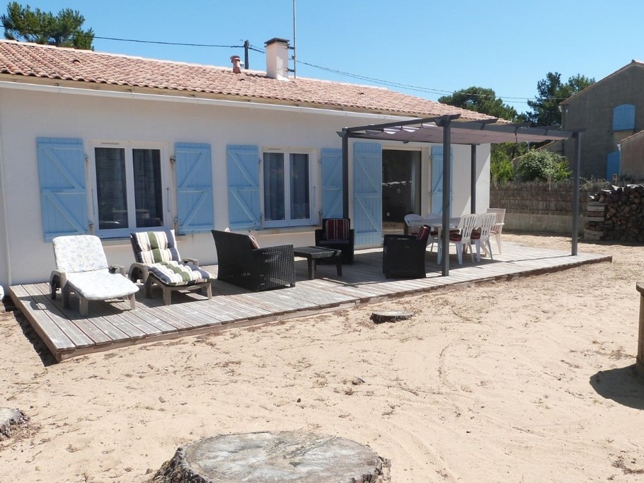 Jardin sablonneux avec salon de jardin et pergola