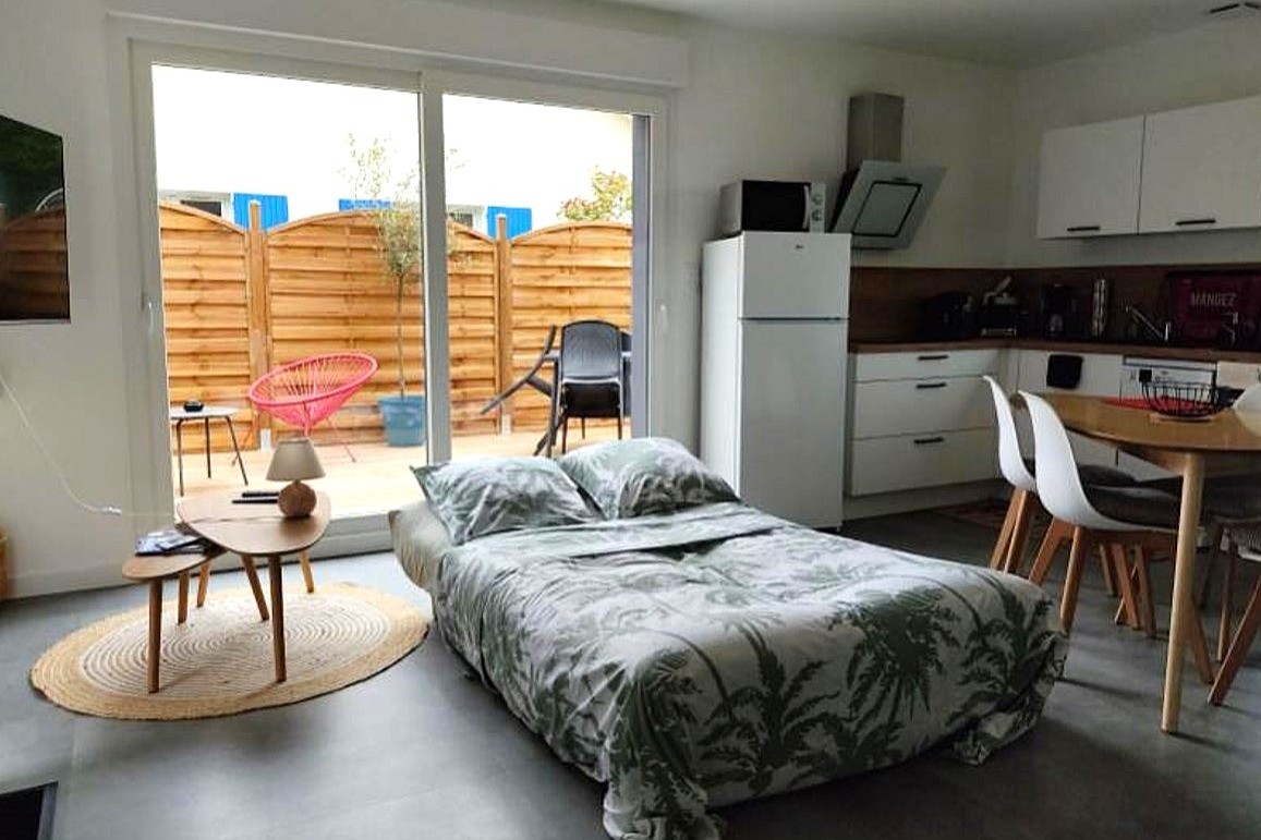 Pièce de vie au rez-de-chaussée avec coin salon avec TV, et coin cuisine et sa table à manger.  Canapé convertible pour 2 personnes. Terrasse en bois accessible par un portillon ou par la baie vitrée.