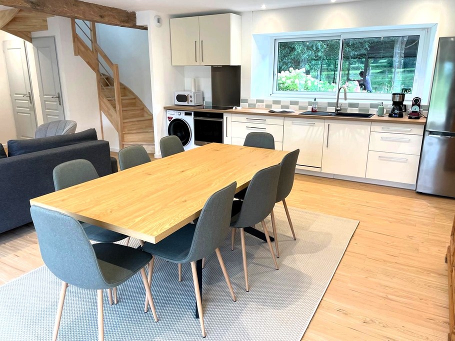 Grande pièce de vie avec salon (poêle à bois, smart TV), séjour et cuisine ouverte parfaitement équipée.