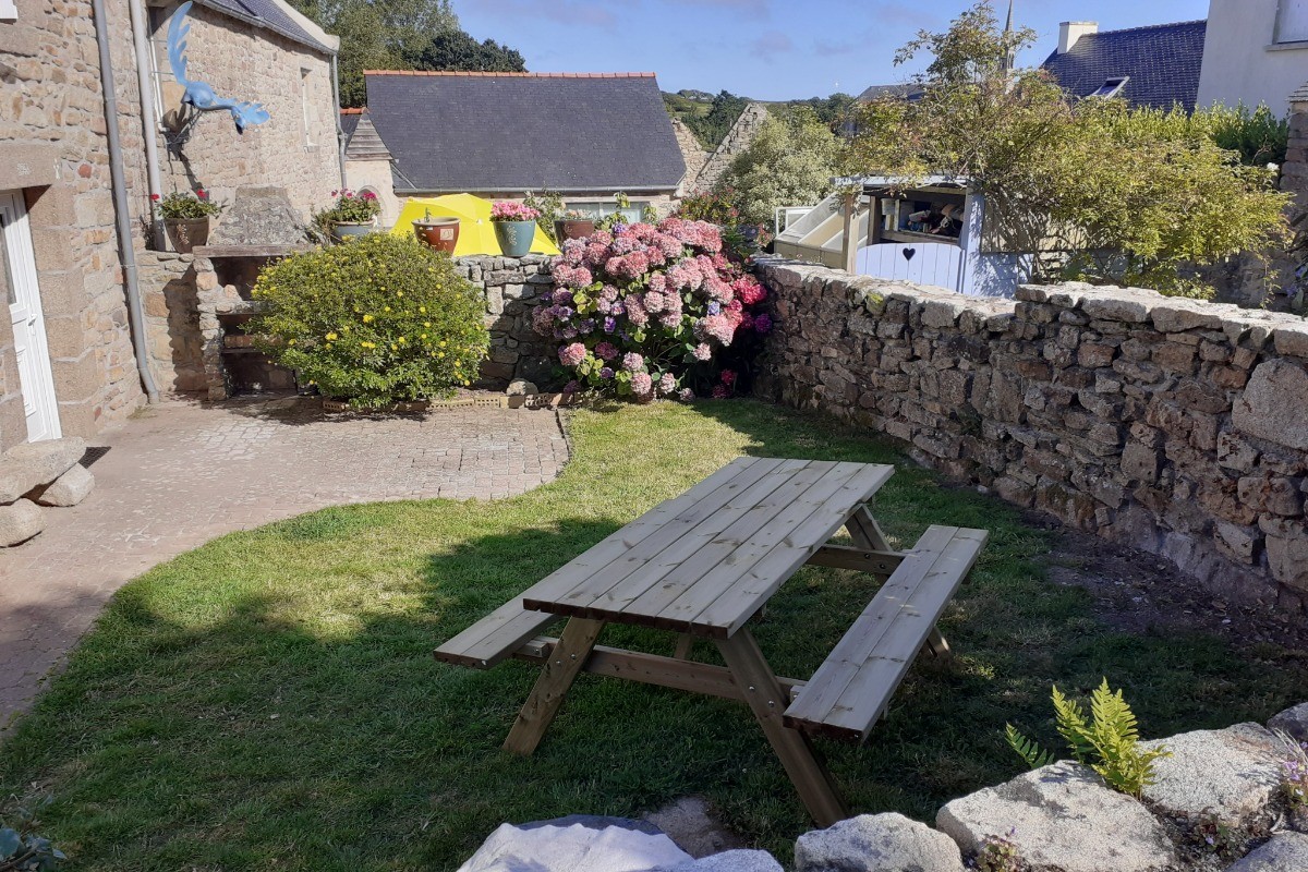Jardin clos avec table de jardin et barbecue.