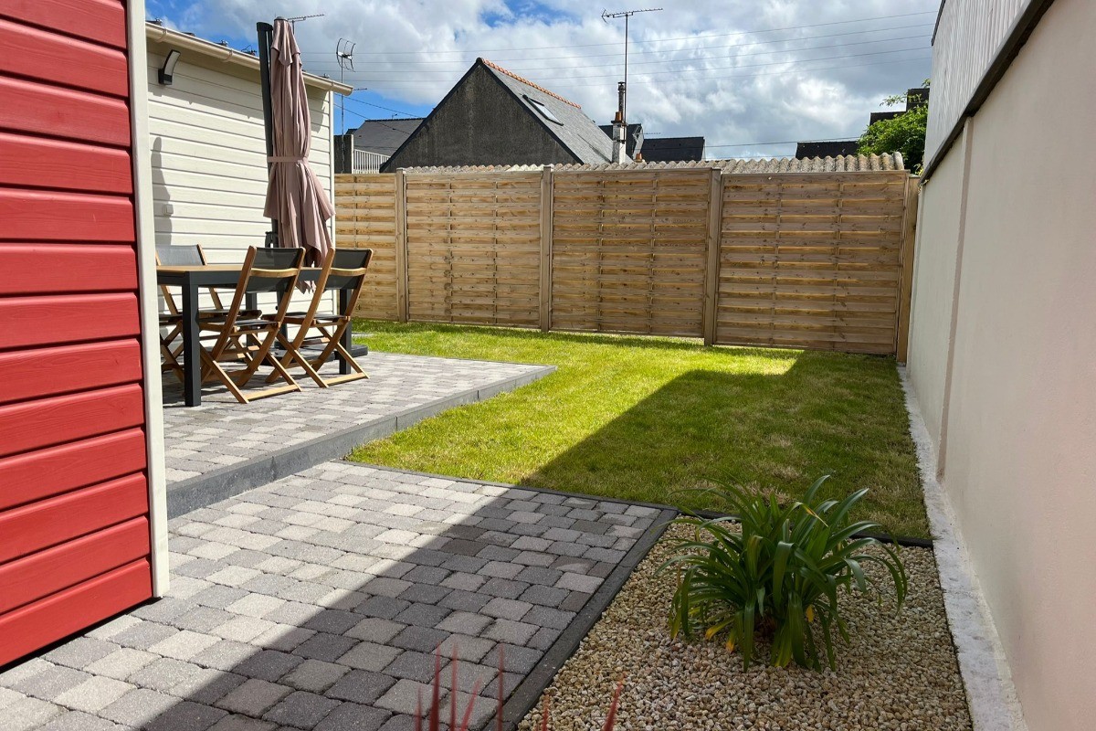 Allée sur le côté de la maison menant à la porte à la terrasse, au jardinet et à la porte d'entrée.