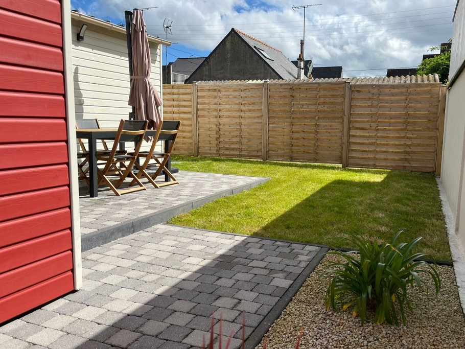 Allée sur le côté de la maison menant à la porte à la terrasse, au jardinet et à la porte d'entrée.