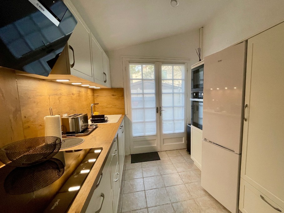 Vue inversée, plaque de cuisson induction, hotte, plan de travail, placard de rangement courses.