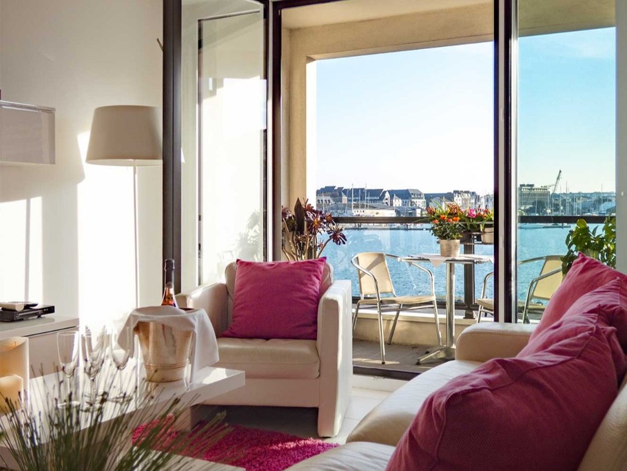 Pièce de vie très lumineuse avec coin salon, coin séjour et coin cuisine. Vue sur le port de plaisance au pied des remparts de Saint-Malo.