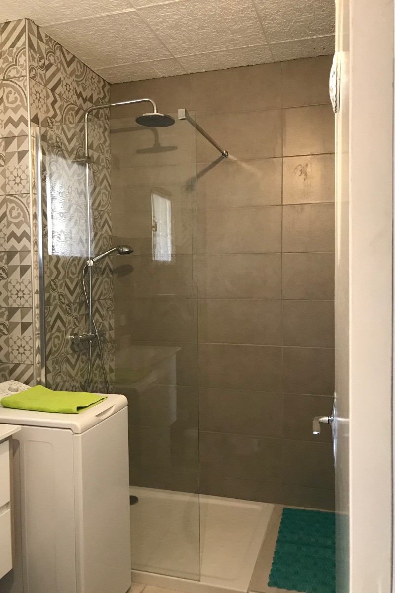 salle de bain avec machine à laver le linge et douche italiènne