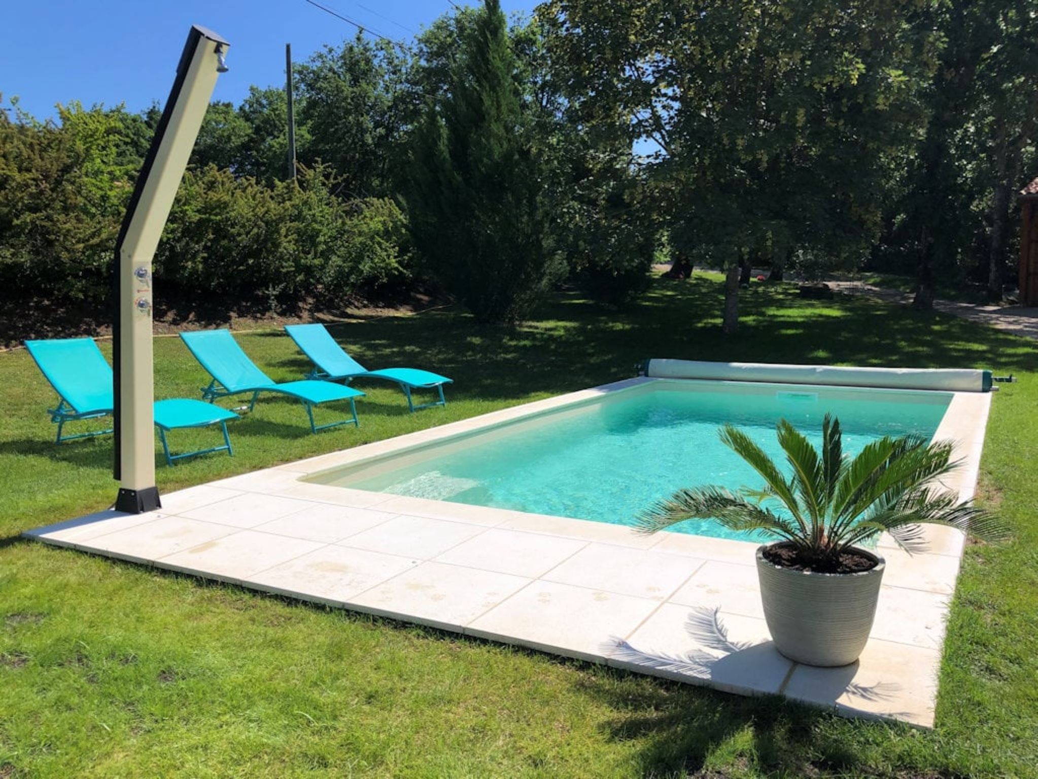 Piscines avec chaises longues et douche extérieure