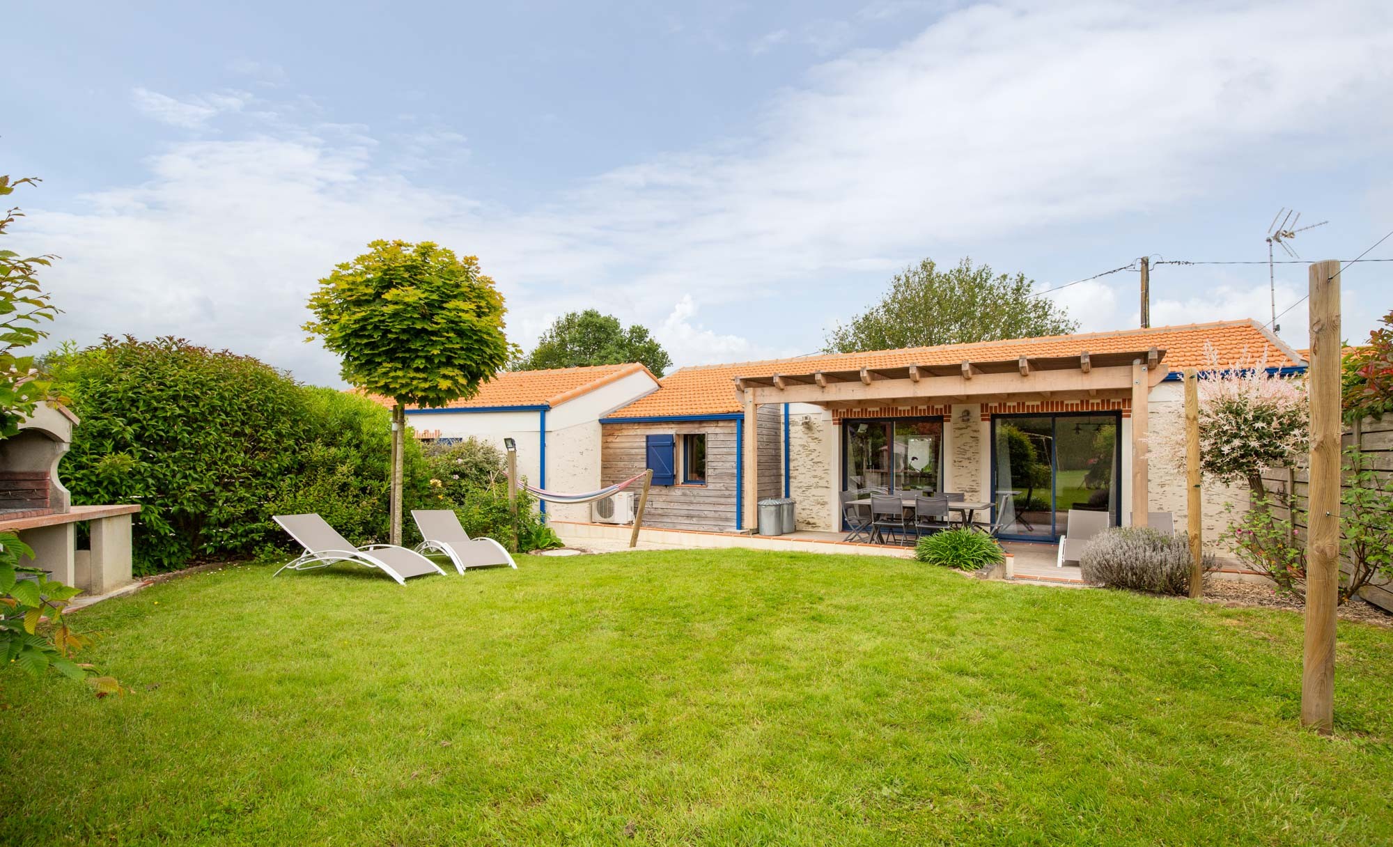 Jardin privatif avec pergola, hamac, salon de jardin, bain de soleil, barbecue et fils à linge.