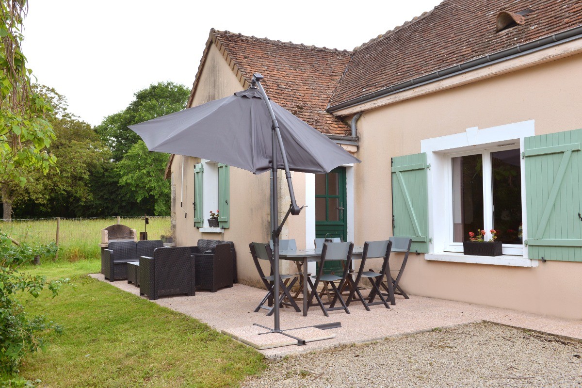 Table et salon de jardin sur la terrasse devant la longère.