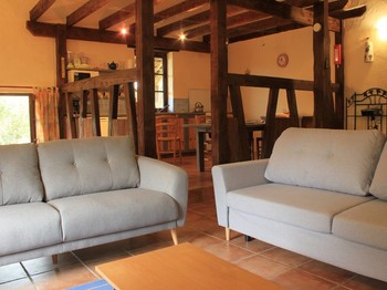 Le salon est ouvert sur l'espace de vie avec de magnifiques poutres apparentes