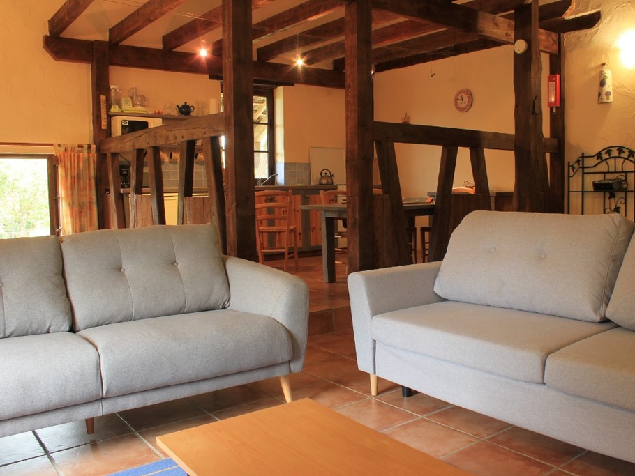 Le salon est ouvert sur l'espace de vie avec de magnifiques poutres apparentes