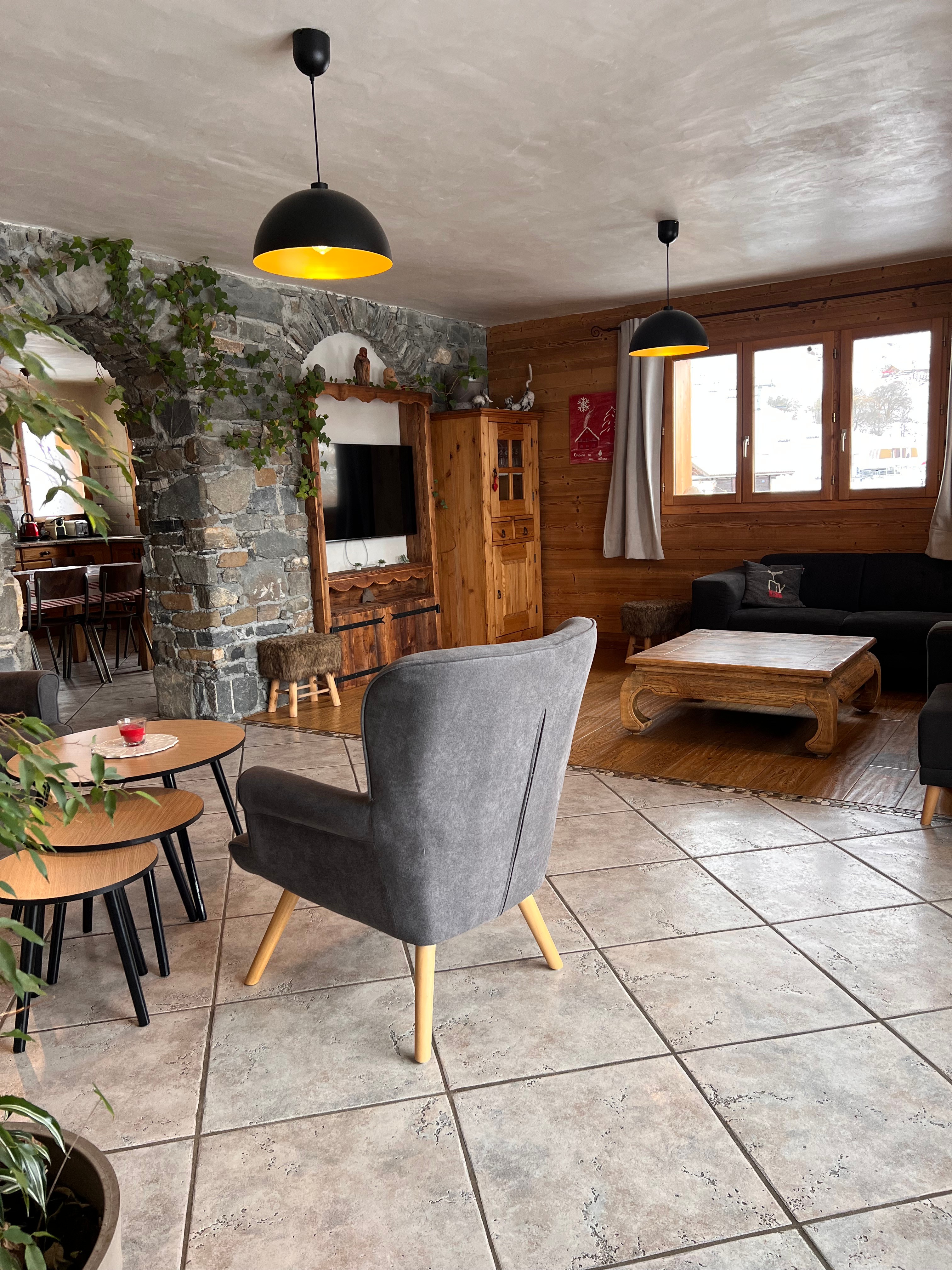 Salon avec télévision et poêle à bois, offrant une vue imprenable sur les montagnes et un accès direct à la terrasse.