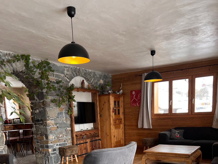 Salon avec télévision et poêle à bois, offrant une vue imprenable sur les montagnes et un accès direct à la terrasse.