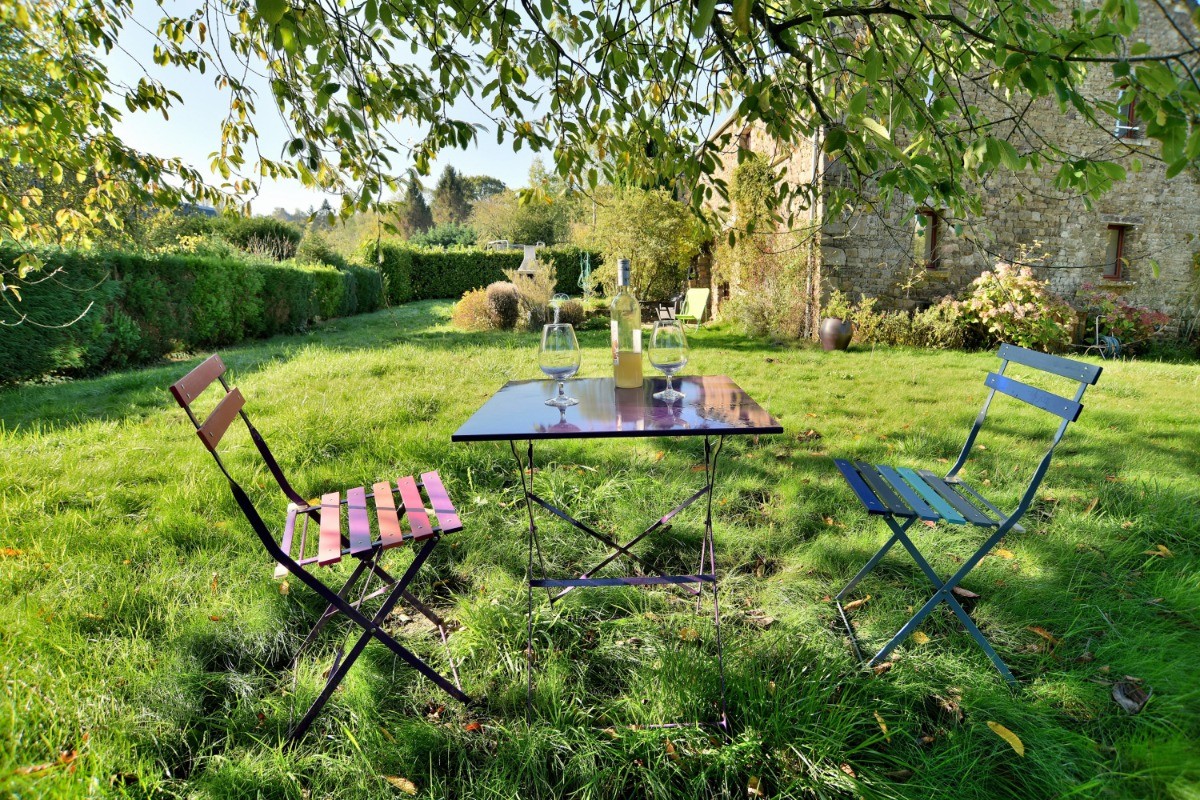 Façade arrière de la maison : terrasse, barbecue, jardin arboré, carré d'aromatiques.