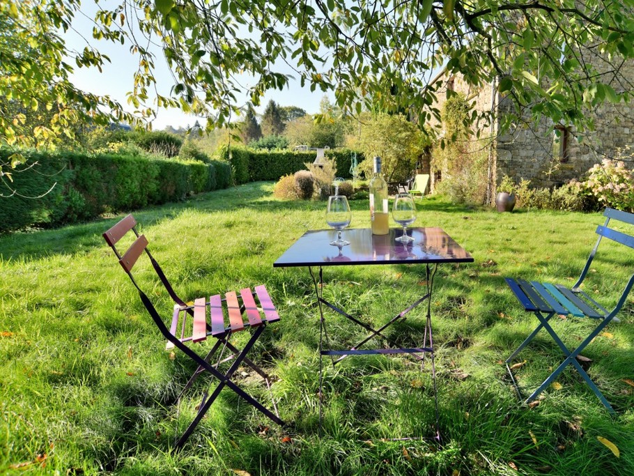 Façade arrière de la maison : terrasse, barbecue, jardin arboré, carré d'aromatiques.
