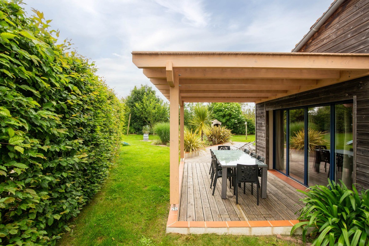 Jardin privatif avec terrasse, transats, salon de jardin, pergola, barbecue et fils à linge.