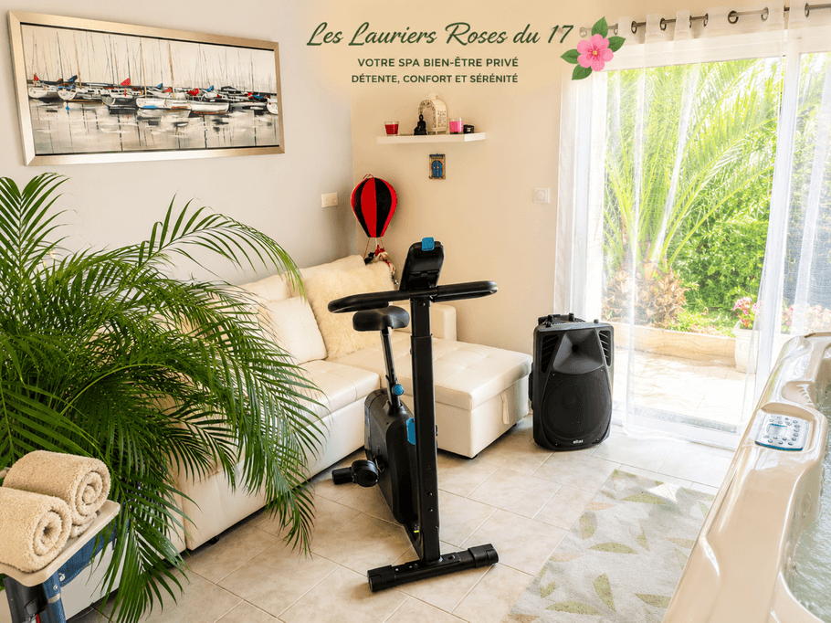 In the conservatory opening onto the garden, there is a sofa, an exercise bike and a hot tub at Gîte Les Lauriers Roses du 17 in Charente-Maritime, accommodating 2 to 4 people, with a hot tub