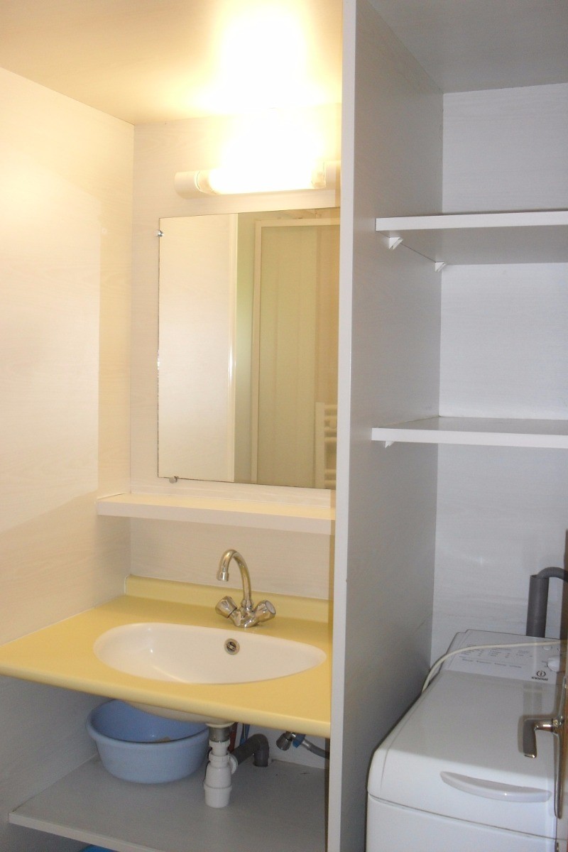 Salle d'eau avec douche, lavabo, radiateur sèche-serviettes et lave-linge.
