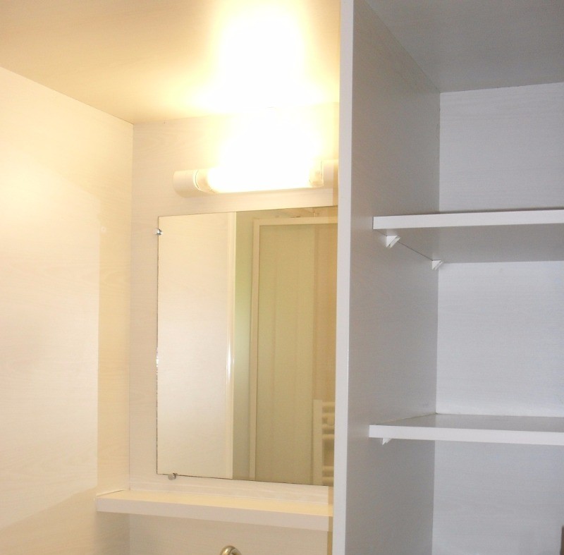 Salle d'eau avec douche, lavabo, radiateur sèche-serviettes et lave-linge.