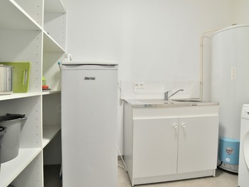 Arrière-cuisine avec second réfrigérateur et évier. Espace buanderie à droite avec lave-linge.