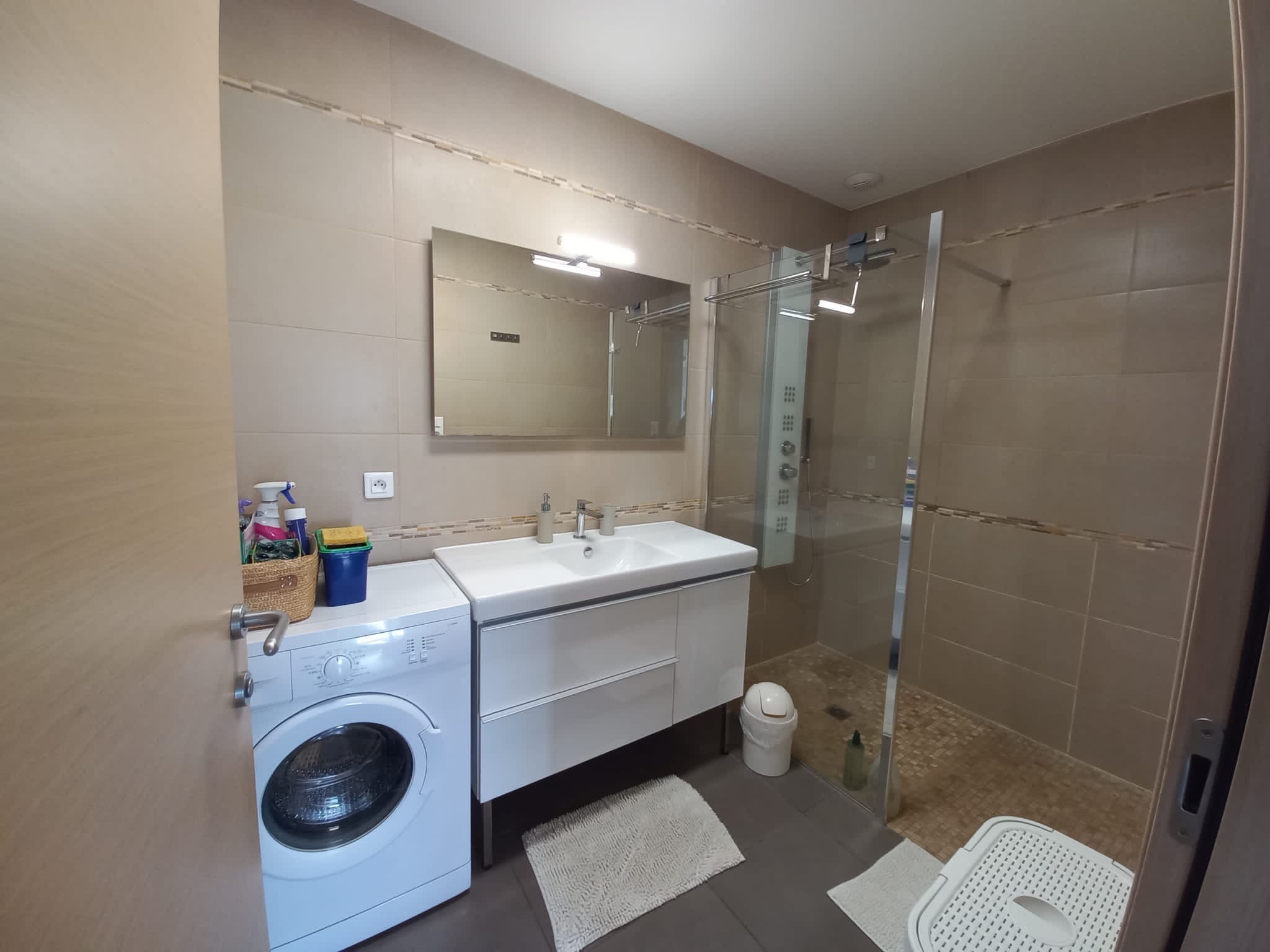 salle de bain avec douche américaine, lavabo et lave linge