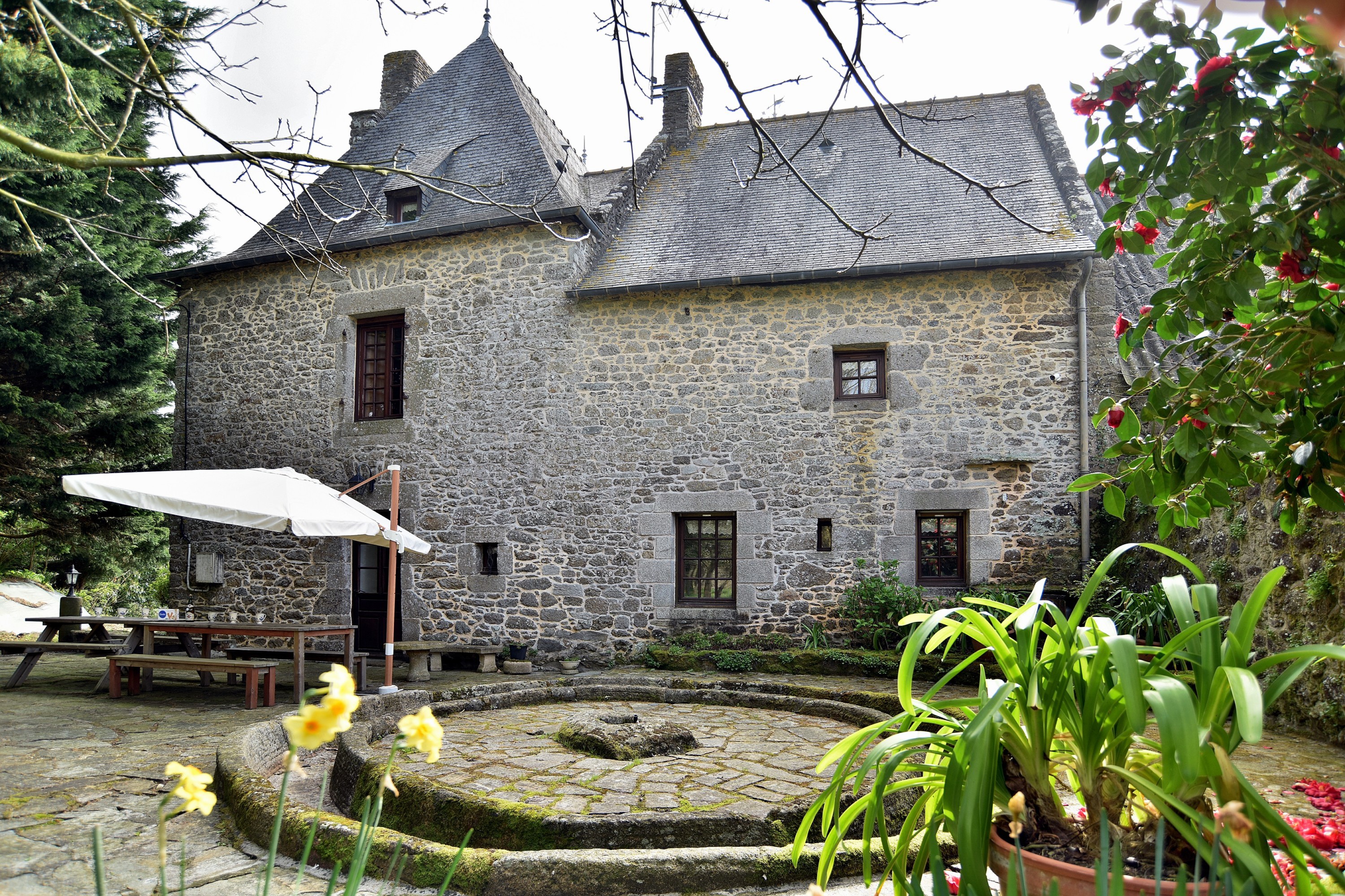 La terrasse avec mobilier de jardin et la roue de pressoir en granit