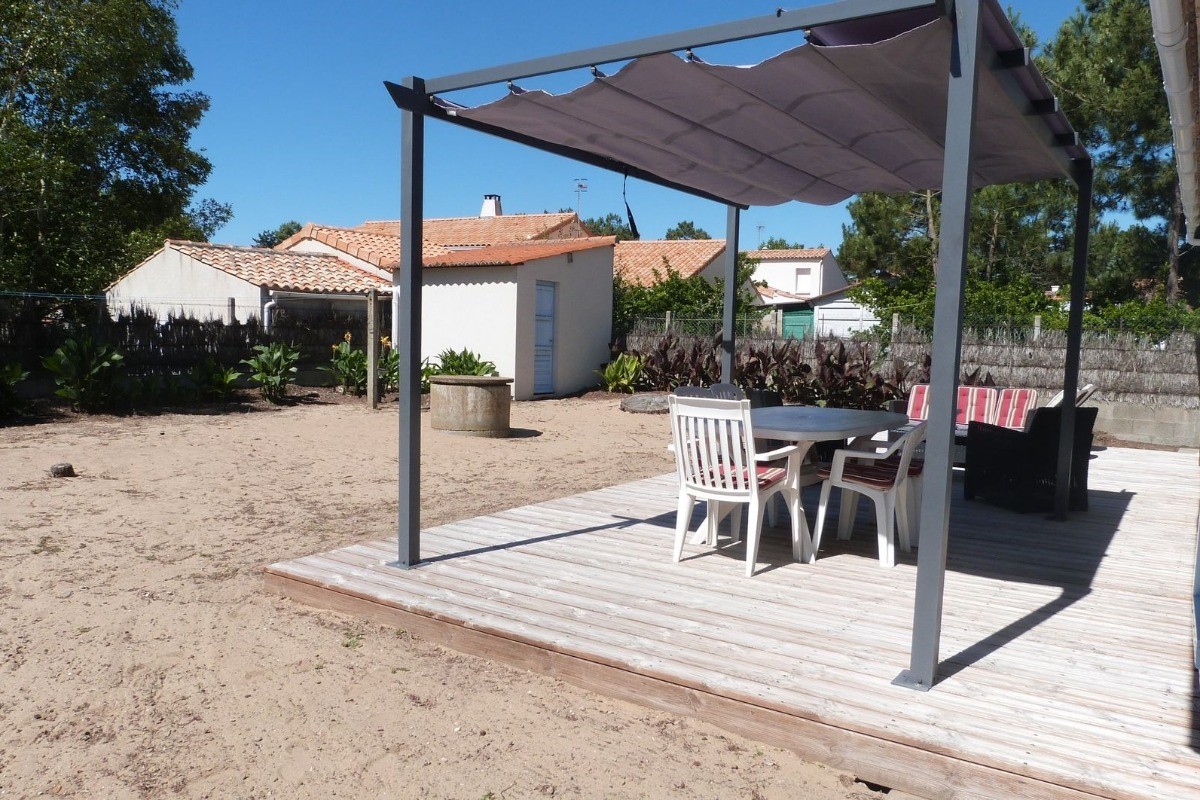 Jardin sablonneux avec salon de jardin et pergola