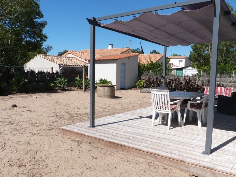 Jardin sablonneux avec salon de jardin et pergola