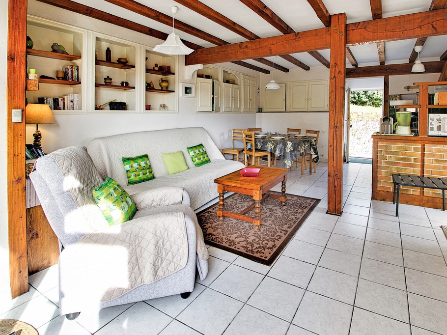 Espace salon détente, un canapé clic-clac confortable, un fauteuil relax, une table basse et un coin bibliothèque, ainsi que des brochures touristiques.