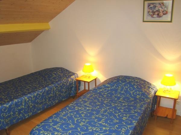 Chambre jaune climatisée avec 2 lits de 90 cm et point d'eau