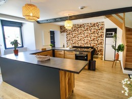 Pièce de vie au rez-de-chaussée avec sa cuisine ouverte, un coin séjour, un coin salon. 2 escaliers de part et d'autres desservent les 2 chambres.