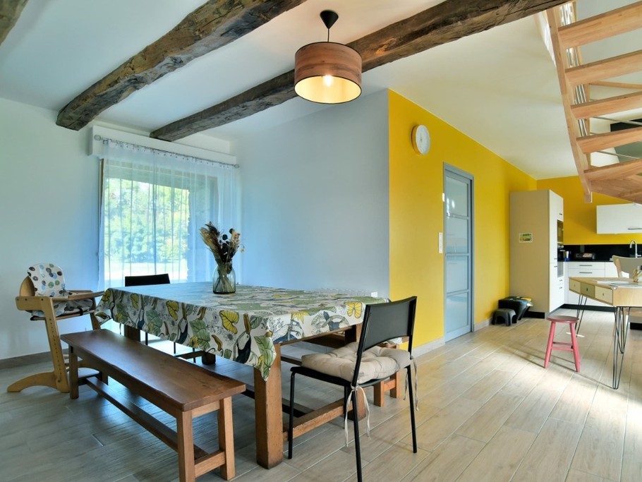 Grande pièce de vie avec poutres apparentes. En enfilade coin salon, coin séjour, coin bureau et coin cuisine.