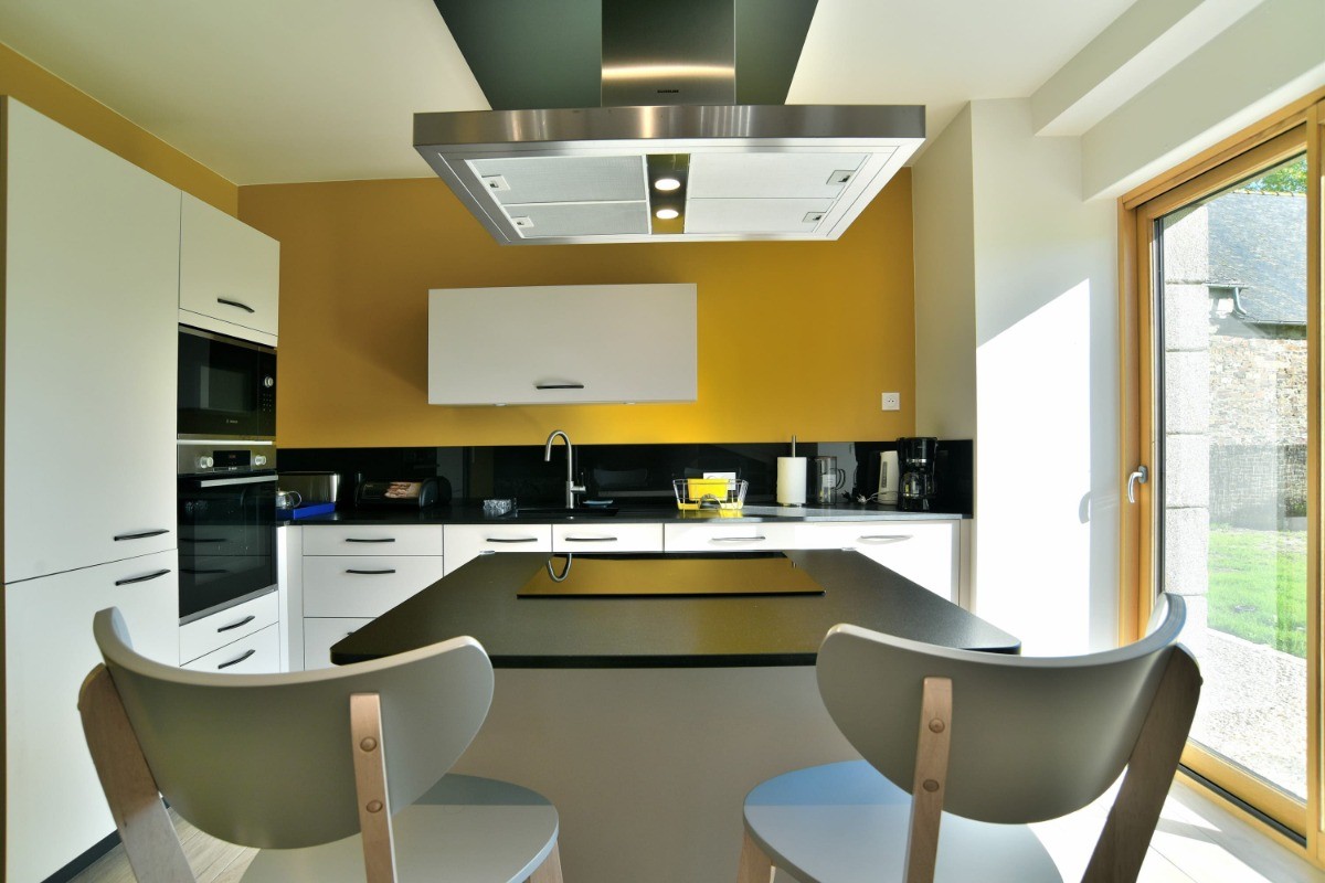 Cuisine colorée et lumineuse, toute équipée. Un ilot central avec 2 chaises hautes.