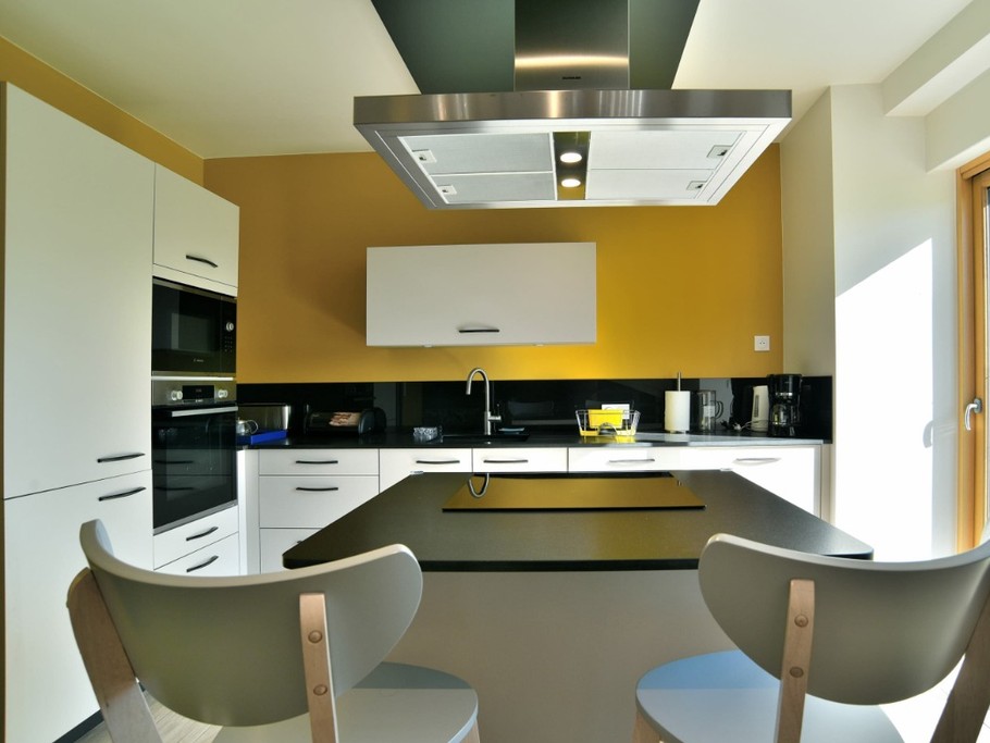 Cuisine colorée et lumineuse, toute équipée. Un ilot central avec 2 chaises hautes.