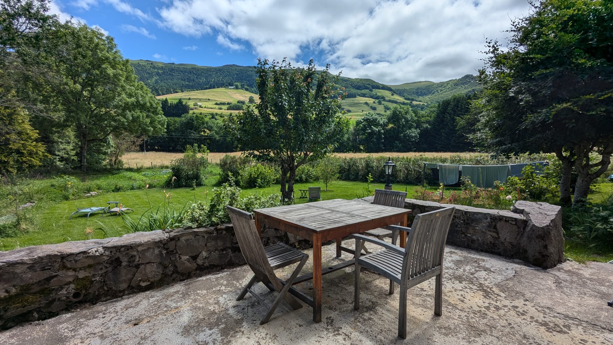 Terrace of the gîte with panoramic view of the Cantal mountains at Le Claux