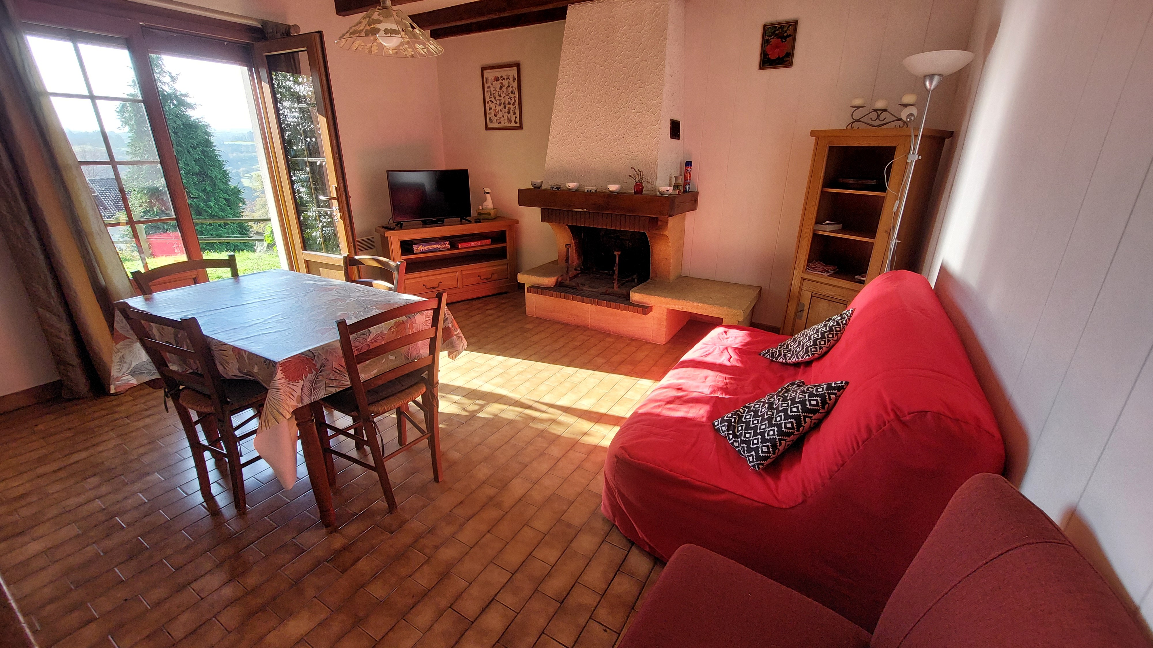 Salon lumineux avec cheminée et accès direct sur l’extérieur du gîte.