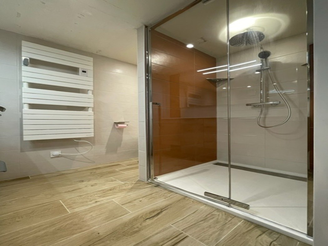 Salle d'eau moderne avec grande douche à l'italienne, carrelage contemporain et éclairage chaleureux