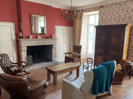 Salon lumineux avec cheminée en pierre, fauteuils en cuir et décoration chaleureuse dans une maison de caractère à Saint-Simon
