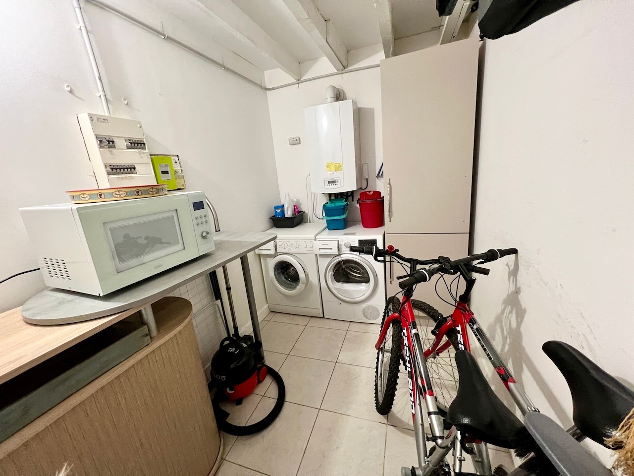 Laundry room with large fridge-freezer, microwave and two bicycles.