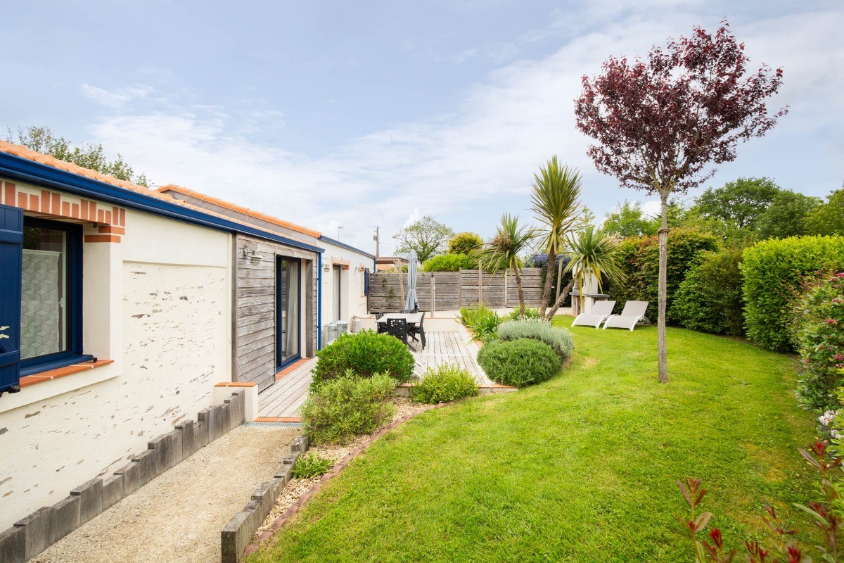 Jardin privatif avec terrasse, salon de jardin, transats, parasol, barbecue et fils à linge.