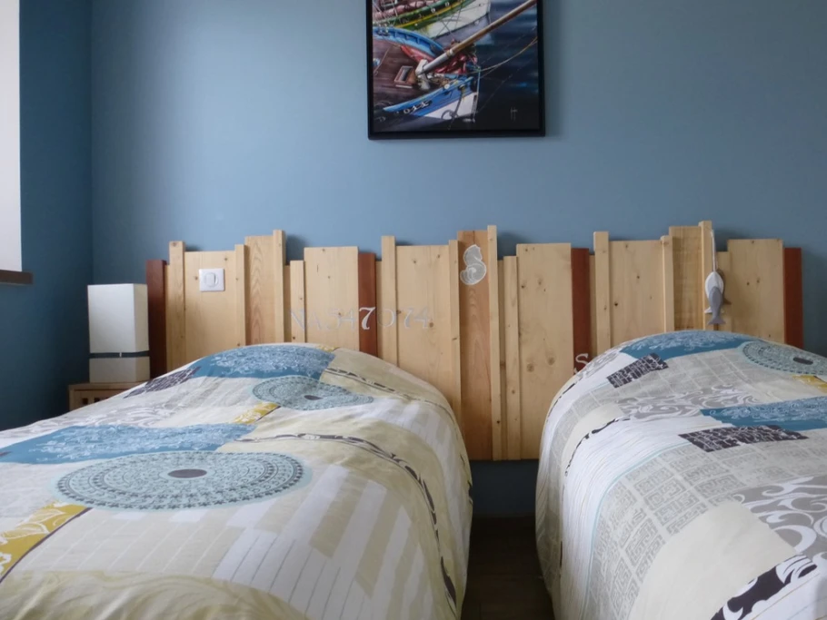 Blue bedroom with two single beds, wardrobe and TV.