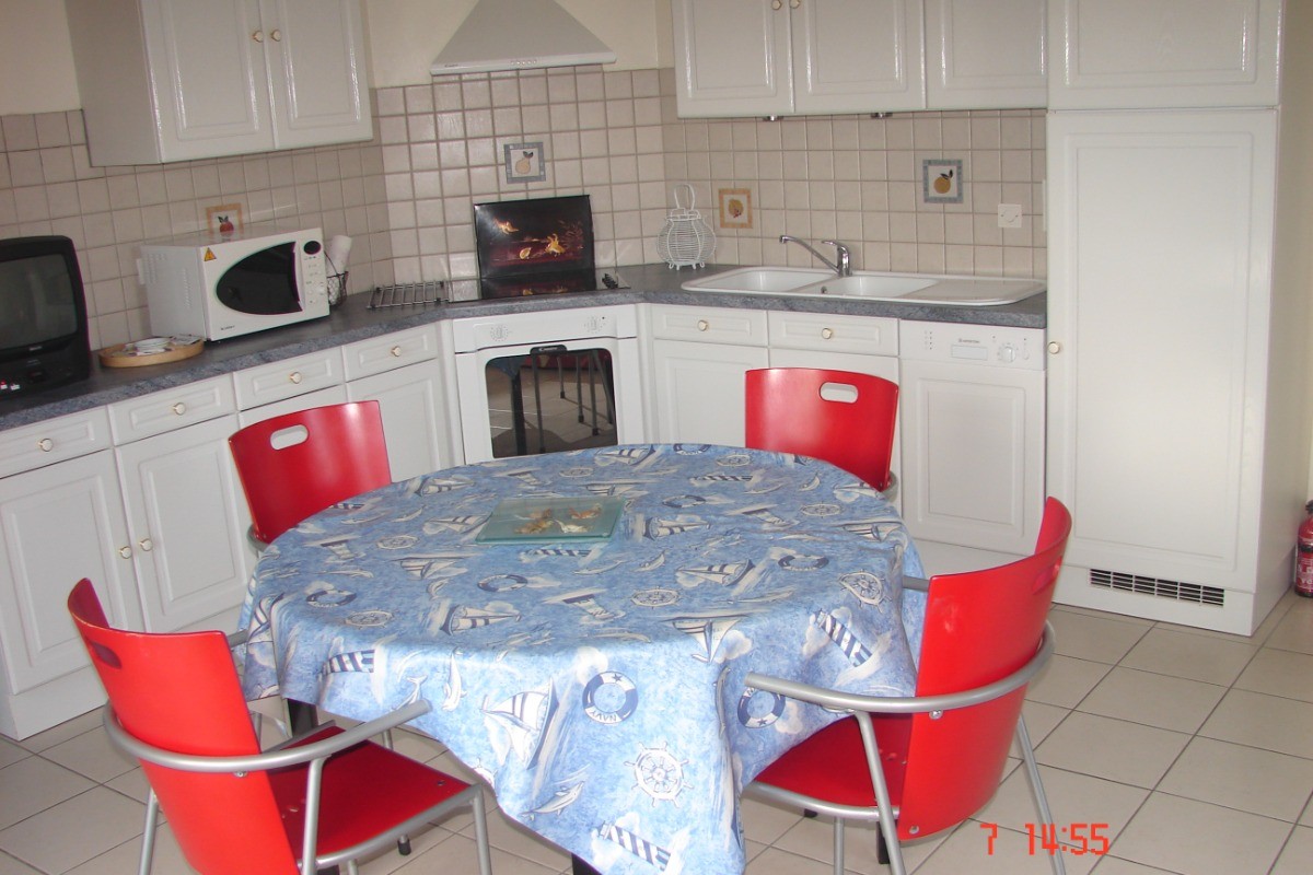 Coin repas avec cuisine aménagée et lave vaisselle.