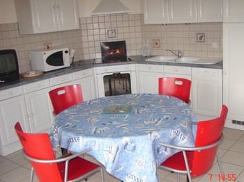 Coin repas avec cuisine aménagée et lave vaisselle.