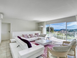 Grand salon avec télévision. De cette pièce de vie on rejoint par de grandes baies vitrées le balcon qui offre une splendide vue panoramique sur la mer et la baie de Cavalaire-sur-Mer