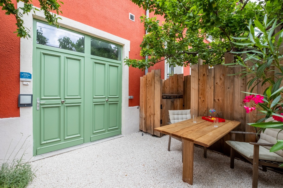 Patio à l'entrée aménagé avec table et chaise en accès libre et partagé avec les deux autres logements.