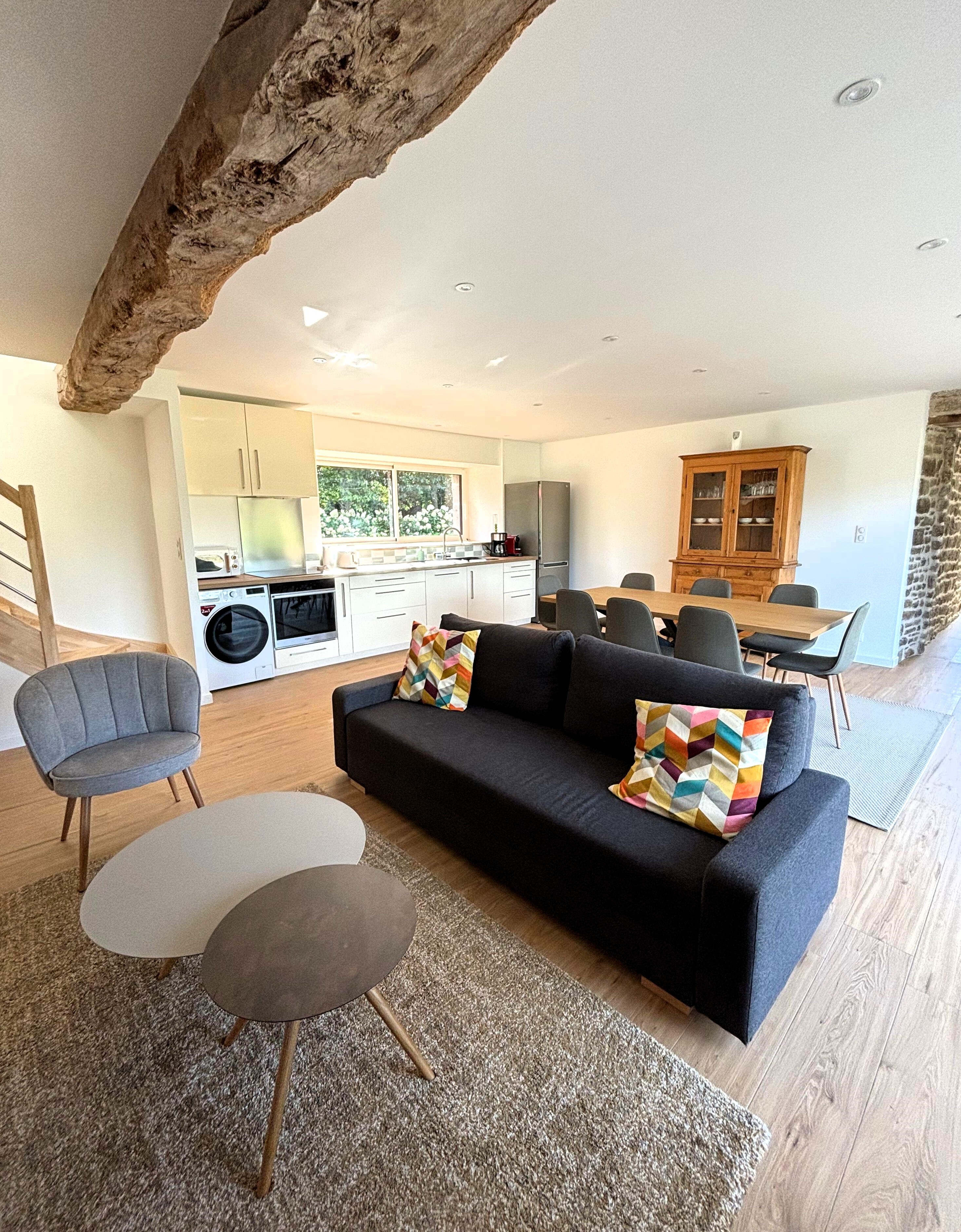 Grande pièce de vie avec salon (poêle à bois, smart TV), séjour et cuisine ouverte parfaitement équipée.