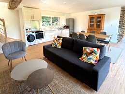 Grande pièce de vie avec salon (poêle à bois, smart TV), séjour et cuisine ouverte parfaitement équipée.