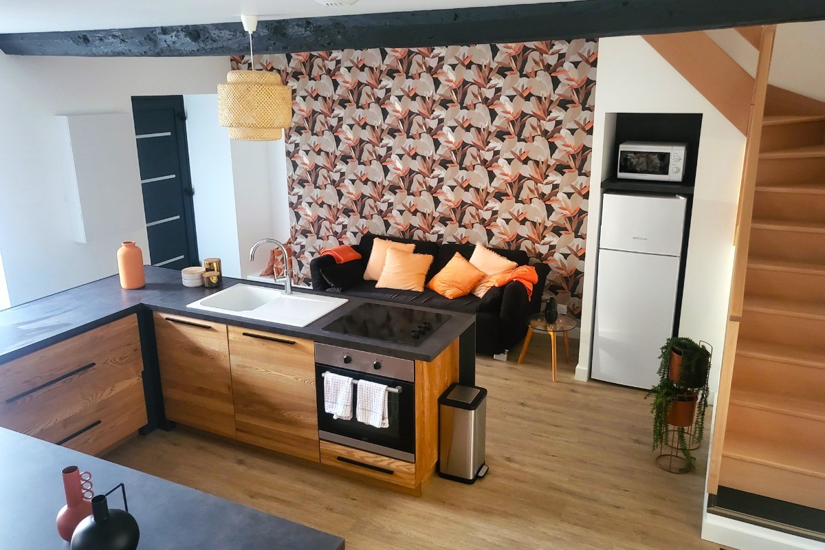 Pièce de vie au rez-de-chaussée avec sa cuisine ouverte, un coin séjour, un coin salon. 2 escaliers de part et d'autres desservent les 2 chambres.