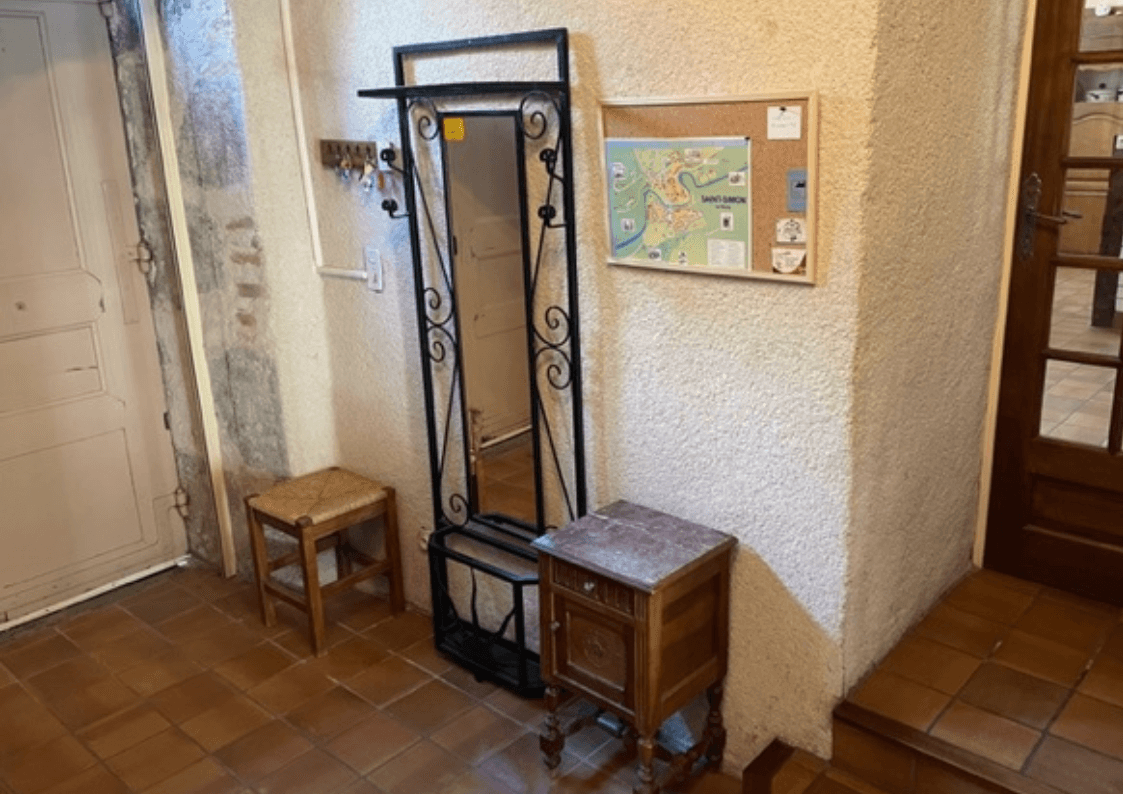 Hall d’entrée lumineux avec détails en bois et pierres apparentes, typiques des maisons de caractère